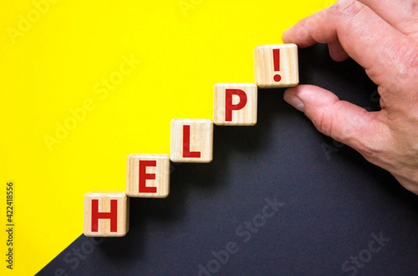 Fototapeta Support and help symbol. Wooden cubes with the word 'help'. Businessman hand. Business, psychology, support and help concept. Beautiful yellow and black background, copy space.