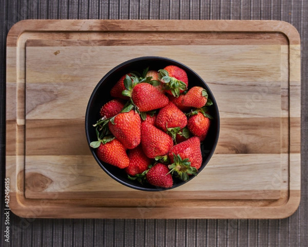 Fototapeta Fresas en un plato sobre una tabla listas para preparar un rico postre