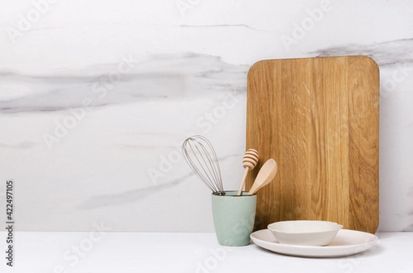Fototapeta Blank wooden board, plates, cup and utensils in it on the white kitchen table.Empty space