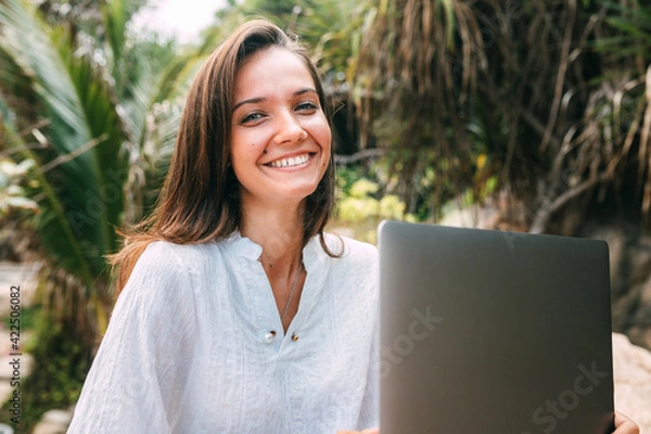 Obraz Close-up portrait of a girl with a beautiful smile sitting with a laptop at work. Freelance girl