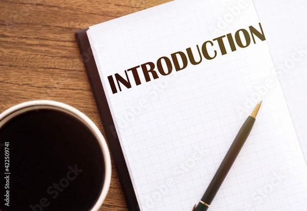 Fototapeta INTRODUCTION - text on notepad on wooden desk.