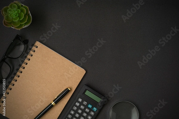 Fototapeta Black vintage alarm clock, calculator, spectacles, notebook and a pen with a copy space on black background. Flat lay.