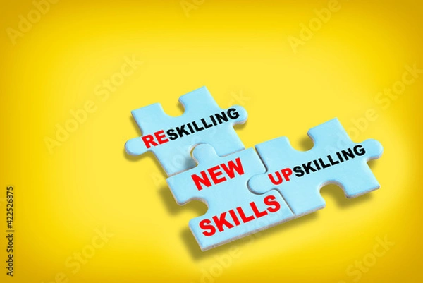 Fototapeta New skills development concept and changing skill demand idea . Reskilling, upskilling and new skills written on blue puzzle isolated on yellow background