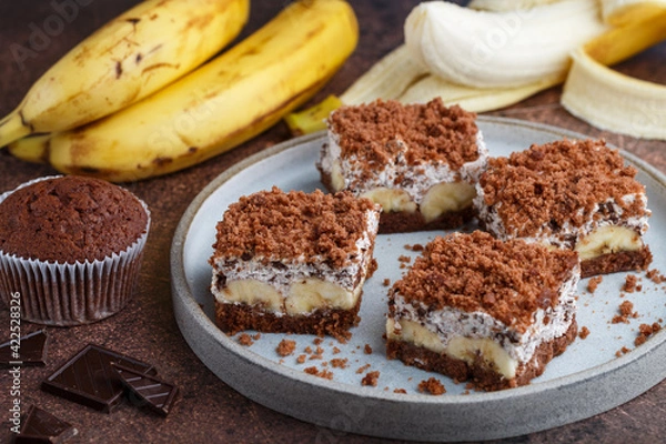 Fototapeta Delicious homemade chocolate dessert with banana, ricotta (cremcheese, mascarpone) and brownie. Mole cake. Portions of pie in a gray plate. Selective Focus