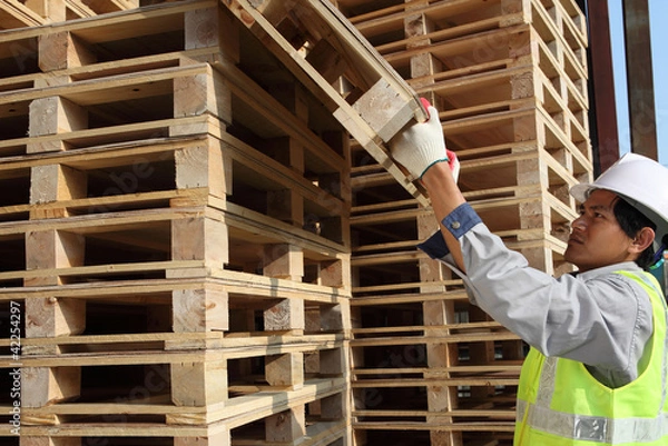 Obraz worker man arranging  pallets in a warehouse