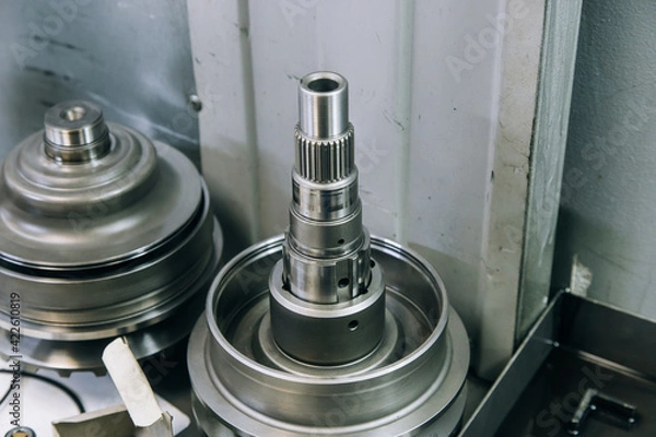 Fototapeta Set of various engine and gearbox spare parts. Shiny gears for planetary gearbox.Metal autotechnology background. wheel engine gears, close up. Automatic transmission in section