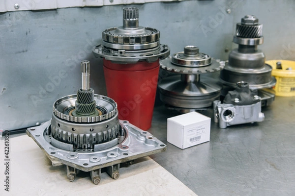 Fototapeta Set of various engine and gearbox spare parts. Shiny gears for planetary gearbox.Metal autotechnology background. wheel engine gears, close up. Automatic transmission in section