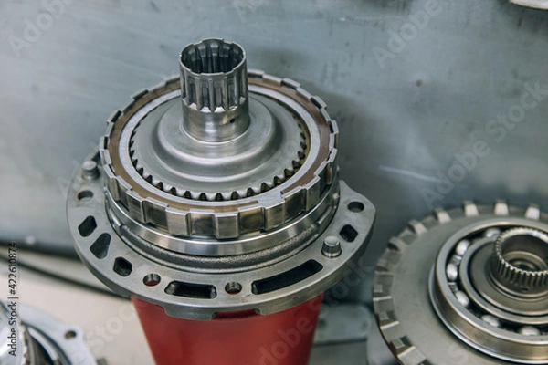 Fototapeta Set of various engine and gearbox spare parts. Shiny gears for planetary gearbox.Metal autotechnology background. wheel engine gears, close up. Automatic transmission in section