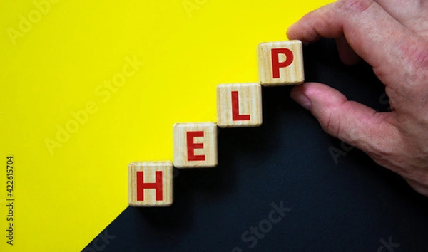 Fototapeta Support and help symbol. Wooden cubes with the word 'help'. Businessman hand. Business, psychology, support and help concept. Beautiful yellow and black background, copy space.