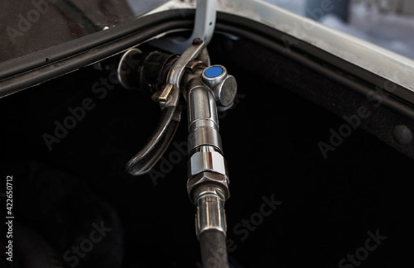 Fototapeta The car is refueled at the gas station through an automatic connector with a high-pressure valve close-up