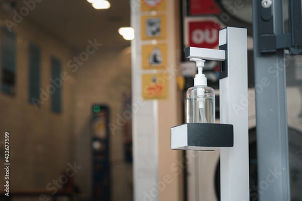 Obraz A bottle of alcohol is placed in front of the door for people to use to wash their hands before entering the building.