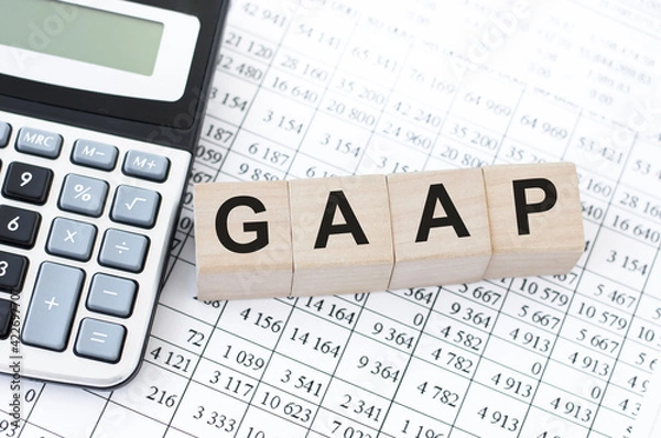 Fototapeta Generally Accepted Accounting Practice. GAAP the word on wooden cubes, cubes are on the table next to the calculator, in the background is a business reports. Business and finance concept