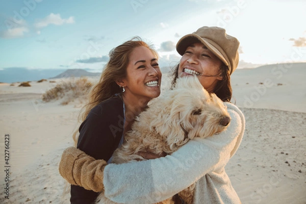 Fototapeta Two beautiful filipino women laughing and hugging each other and their dog