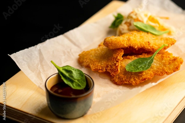 Fototapeta Chicken fillet breaded with sauce. Harmful food.