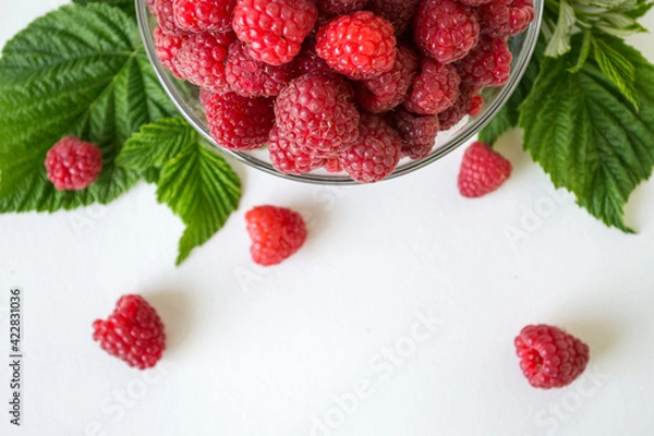 Fototapeta Ripe raspberries with green leaf isolated on white background