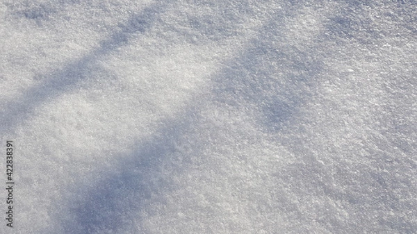 Fototapeta Winter background with snow close-up, top view. On a sunny day outdoors. Pure and shiny snow, with highlights and shadows. Loose gray snow, natural texture. Copy space, no people. 