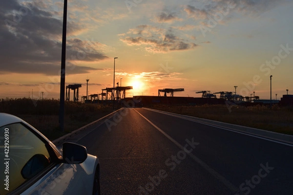 Fototapeta 夕焼けコンテナと車の窓とドアミラーそして地図にまだ無い道