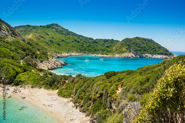 Fototapeta Porto Timoni beach on Corfu island in Greece. Beautiful panoramic view of green mountains, clear sea water, secluded Pirates bay and empty stony beach. Famous destination for summer vacation