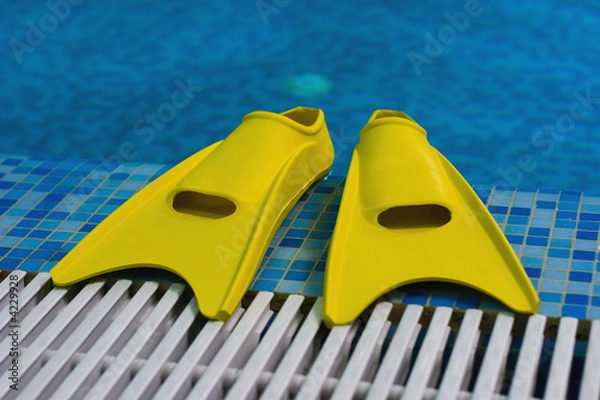 Fototapeta Yellow flippers on coast of swimming pool