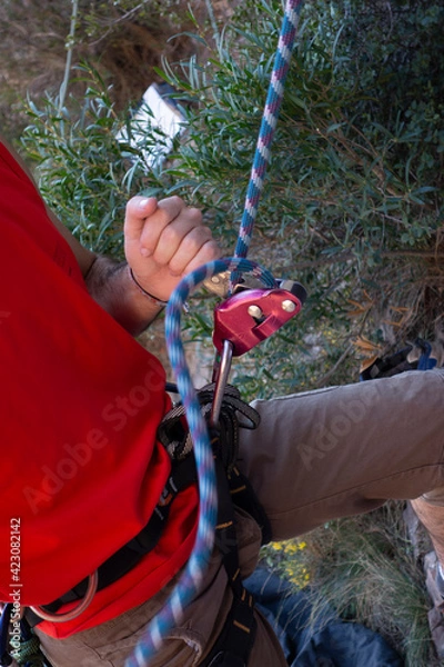 Obraz man climbing a mountain with rope
