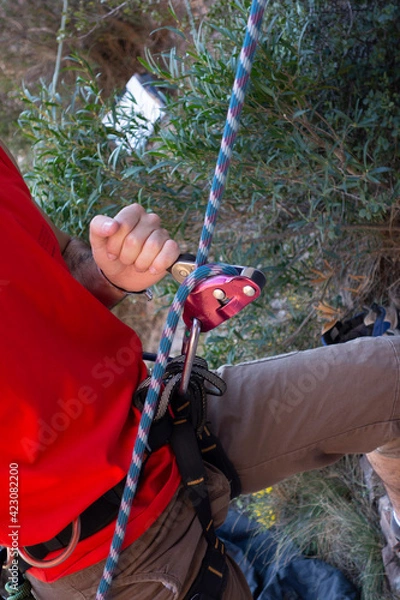 Obraz man climbing a mountain with rope