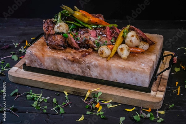 Obraz NY Delmonico 30oz steak with vegetables on marble salt tray.