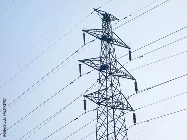 Fototapeta Close up of power poles and towers in the background of blue sky