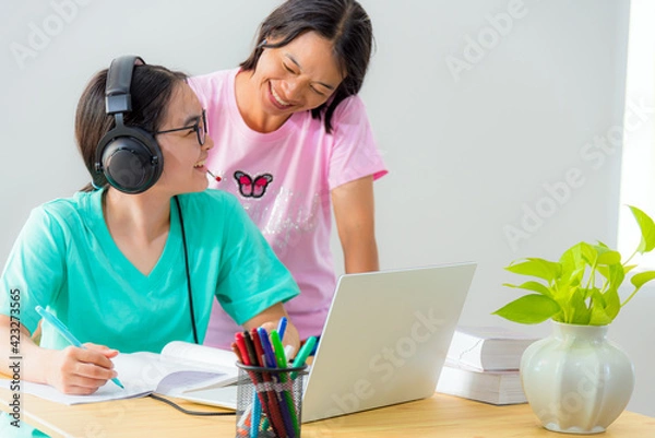 Fototapeta Happy family two Asian woman mother parent is a teacher advice instruction daughter teenage girl student online study from school use a laptop computer education from university class learning at home