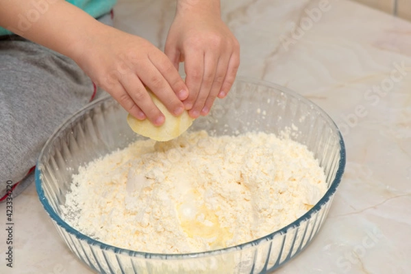 Fototapeta Hands of a child squeezing a lemon on the ingredients of a cake