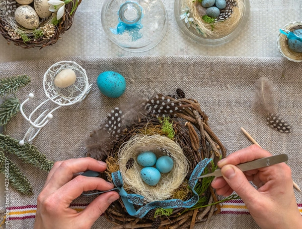 Fototapeta A nest with three white Easter eggs and bunny ears at home on Easter day. Celebrating Easter at spring. Painting eggs.