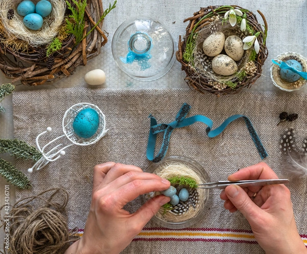Fototapeta A nest with three white Easter eggs and bunny ears at home on Easter day. Celebrating Easter at spring. Painting eggs.