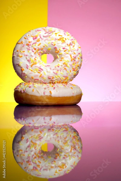 Fototapeta deux donuts blanc sur fond bicolore rose et jaune avec reflet