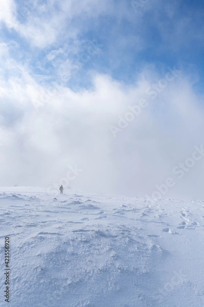 Obraz Man on a snowy mountain under the clouds
