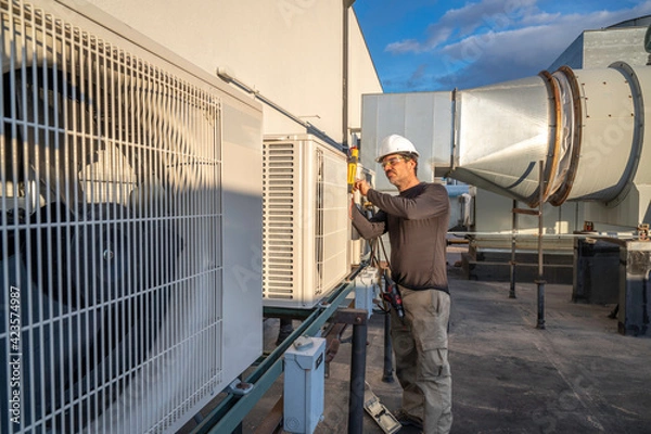 Fototapeta HVAC technician servicing mini-split air conditioners