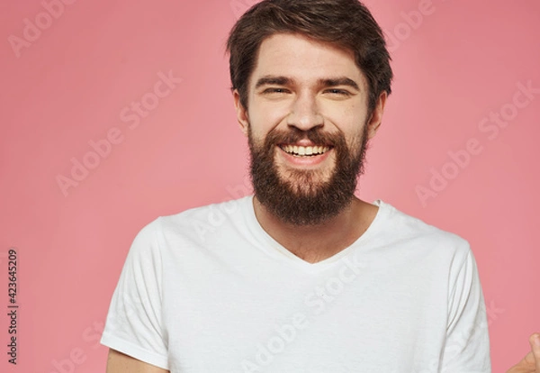 Fototapeta Portrait of a happy man with a beard on a pink background in a white T-shirt