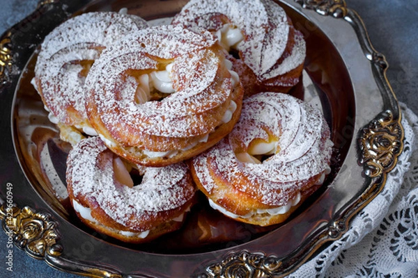 Fototapeta custard cake rings with cream and powdered sugar on a metal platter
