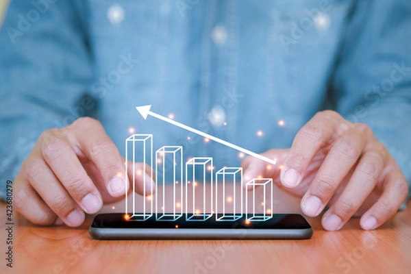 Obraz Businessman used a smartphone and touch the screen with business graph pop up on smart phone. The concept of finance and technology.