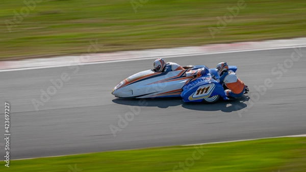 Fototapeta A panning shot of a racing sidecar as it corners on a track.