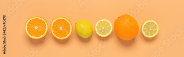 Fototapeta Fresh oranges and lemons in a line on a pastel peach background. Border. View from above.