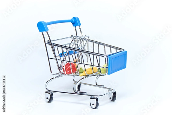 Obraz Blue mini grocery cart from supermarket with groceries on white background. Consumer concept.