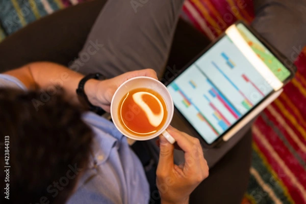 Obraz Man drinking tea near tablet