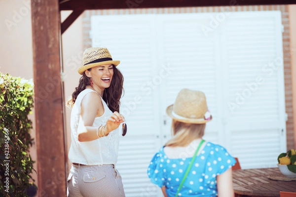 Fototapeta happy stylish mother and child tourists in hats with keys
