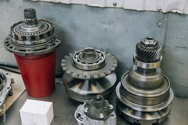 Fototapeta Set of various engine and gearbox spare parts. Shiny gears for planetary gearbox.Metal autotechnology background. wheel engine gears, close up. Automatic transmission in section	