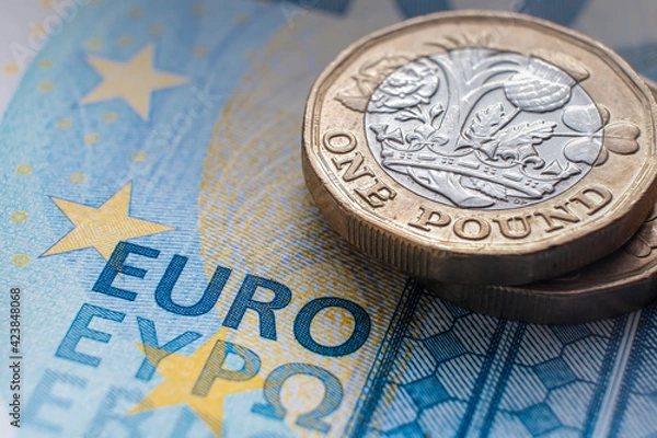 Obraz British one pound coin placed on top of 20 EURO banknote with visible words "EURO" translated in different languages. Concept. Selective focus. Macro.