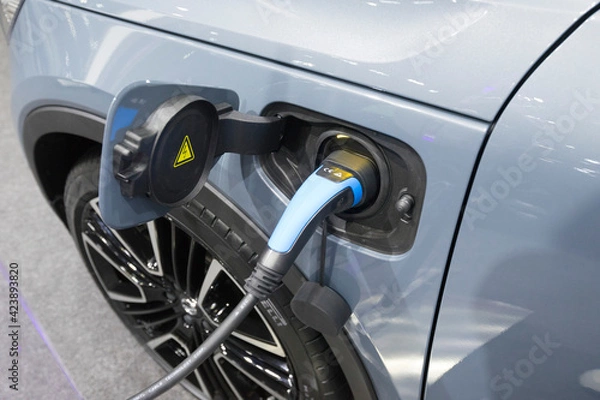 Fototapeta Close up view of vehicle electric charging socket plug in to recharge in Bangkok, Thailand.