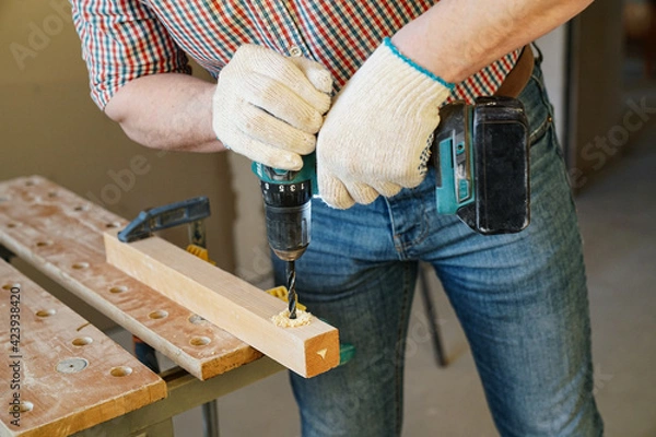 Obraz Worker drills timber with cordless drill