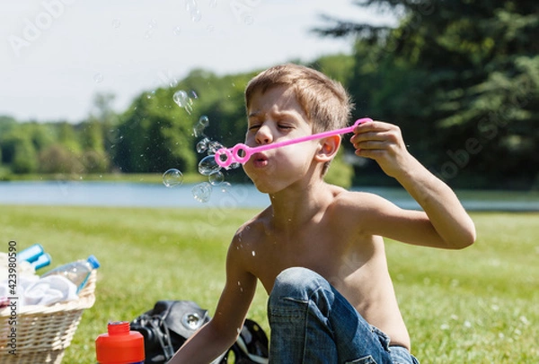 Fototapeta Boy enjoys blowing soap bubbles