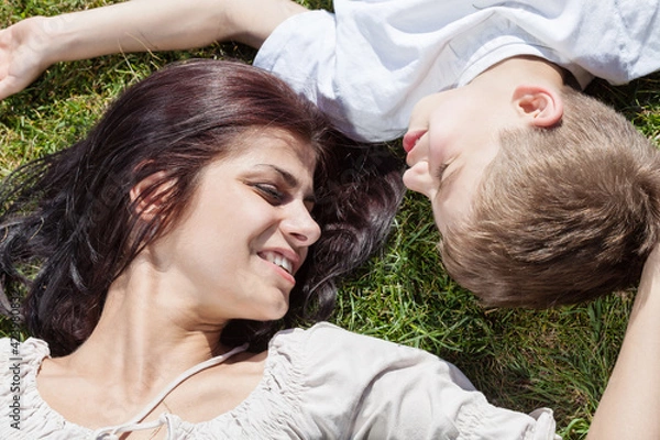 Fototapeta Mother and son lying on the grass head to head