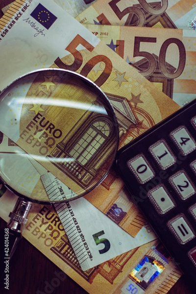 Obraz Euro bills seen through a magnifying glass and a calculator
