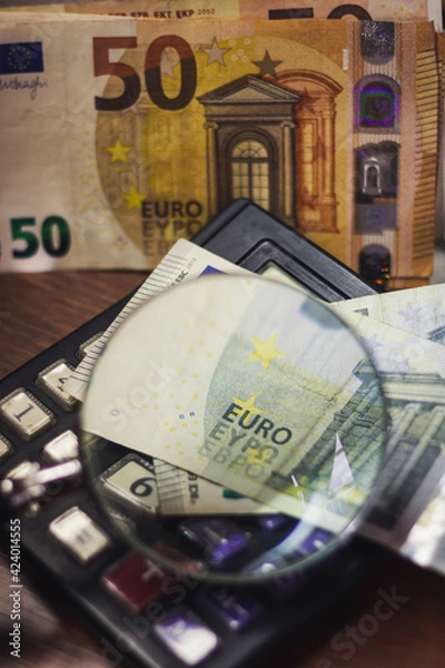 Obraz Euro bills seen through a magnifying glass and a calculator